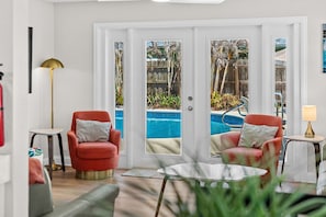 Habitación con vista a la piscina, dos sillones rojos, una mesita y una lámpara.
