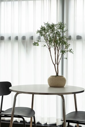 A round table with a potted plant in the center, flanked by two chairs.