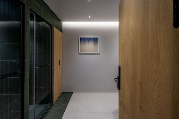 A hallway with a glass door, a wooden door, and a wall-mounted artwork.