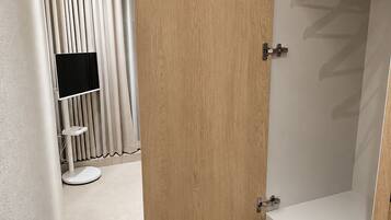 Een hotelkamer met een houten garderobe, een televisie en een kledingrek.