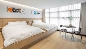 A modern hotel room with a large bed, a small table with chairs, and artwork on the wall. - 88 by James (Dongdaemon-gu)
