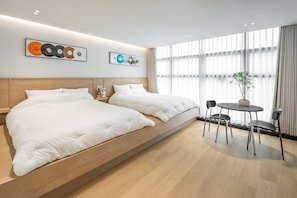 Une chambre d’hôtel moderne avec un grand lit, une petite table avec des chaises et des œuvres d’art accrochées au mur.