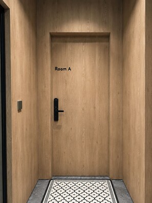 A wooden door with 'Room A' labeled on it, a modern door handle, and a patterned floor mat.