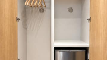 A wardrobe with a hanging rack and a built-in stainless steel mini-fridge.