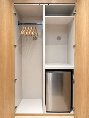 Un armario con una barra para colgar y un mini refrigerador de acero inoxidable integrado.