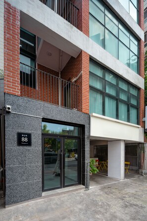 Un edificio moderno con fachada de vidrio, sección de ladrillo y balcón de metal.