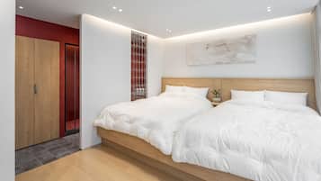 A modern bedroom with a large bed, wooden headboard, and a red accent wall.