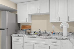 A kitchen with white cabinets, a stainless steel refrigerator, a granite countertop, a sink with a faucet, and a paper towel dispenser. - DC Area Apt w Fenced Yard - 1 Mi to Metro! (Silver Spring)