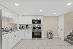 A modern kitchen with white cabinets, a stainless steel oven, and a microwave.