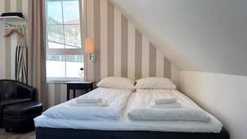 A hotel room with a bed, a chair, a lamp, and a window with a view.