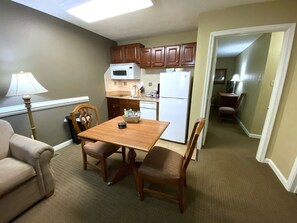 A compact living space with a kitchenette, a dining area with a table and chairs, and a sofa. - Williamsburg | Pool & Family Activities | 1BR Suite (Williamsburg)