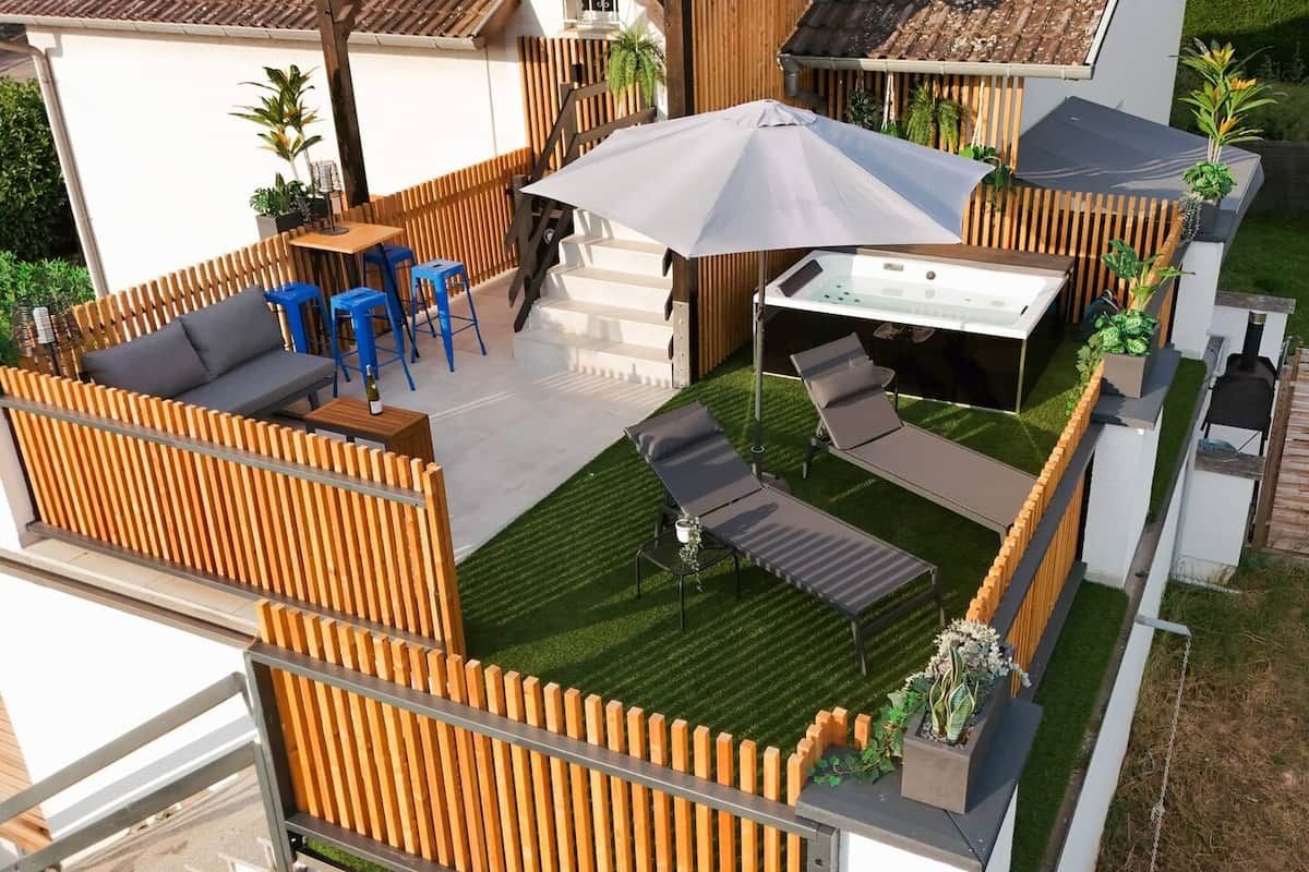A patio area with a sofa, blue chairs, a table, and a grill.