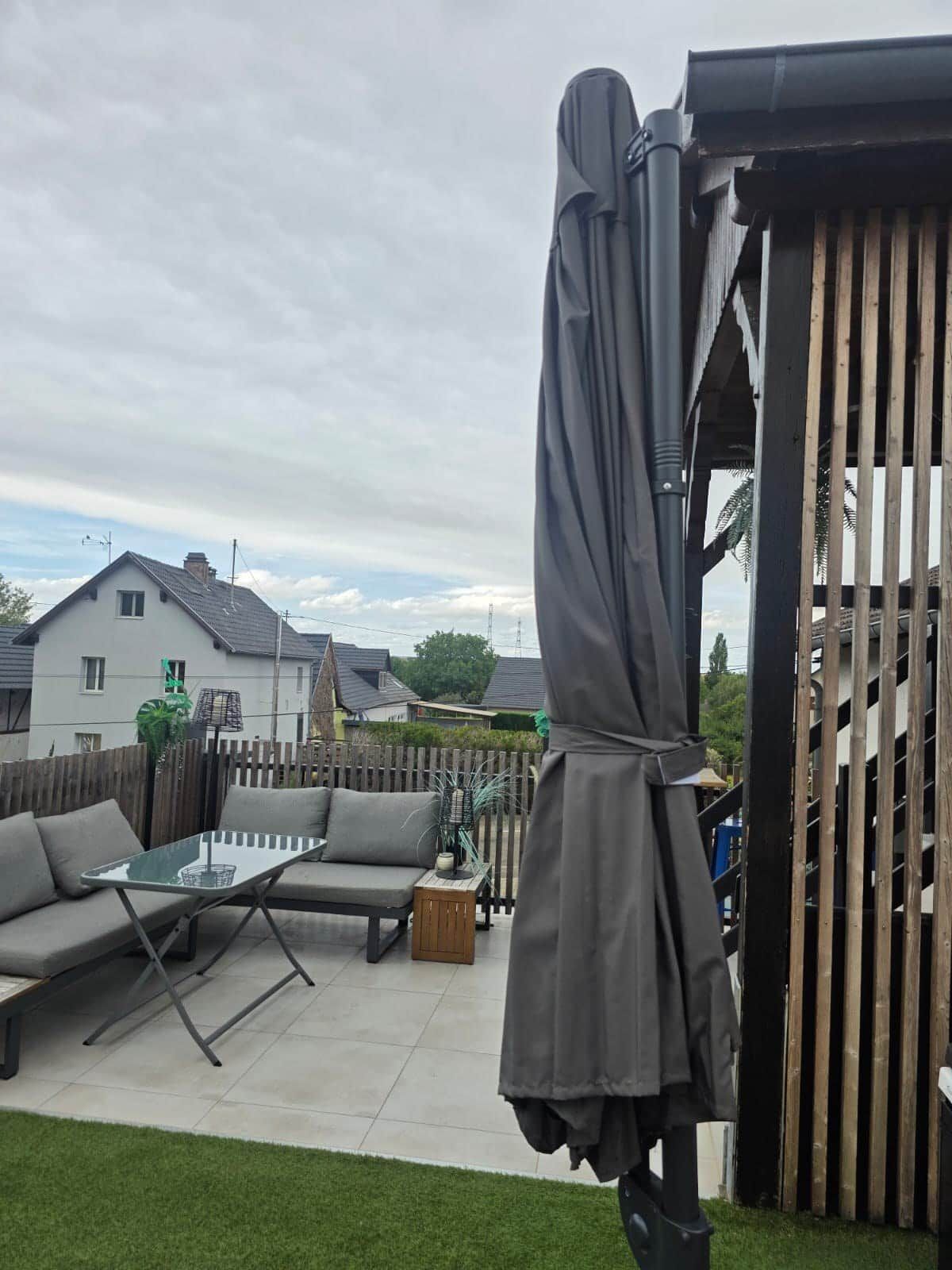 A patio area with a glass table, a sofa, and a covered seating area.