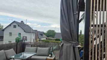 A patio area with a glass table, a sofa, and a covered seating area.