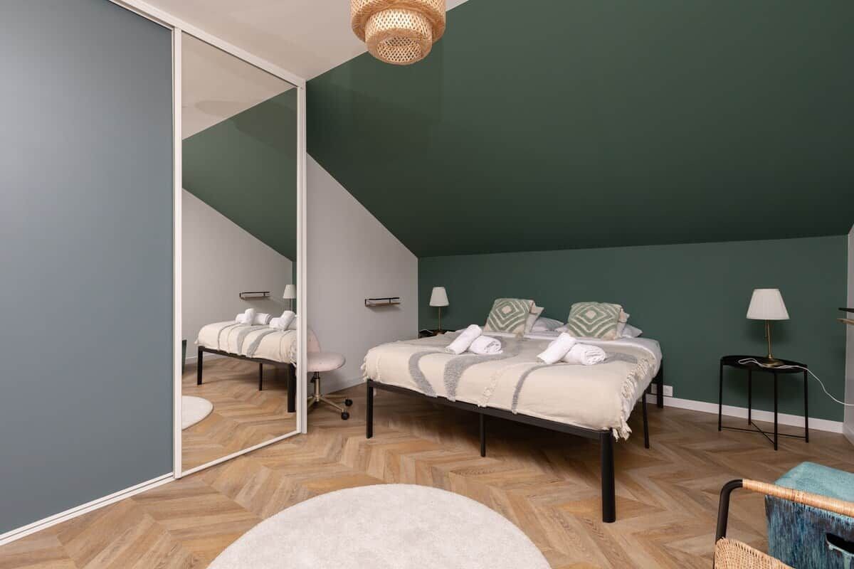 Une chambre à coucher avec un lit, une chaise, un miroir et une lampe.