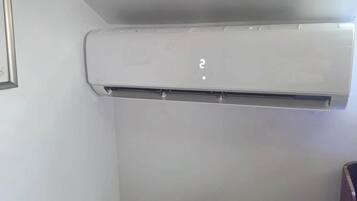 Eine weiße Klimaanlage, an einer Wand in einer Ecke angebracht, über einem Holzboden.