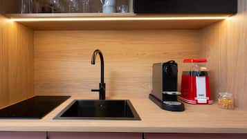 Eine Küche mit einem schwarzen Wasserhahn, einer Kaffeemaschine und einem Zuckerlöffelstander.