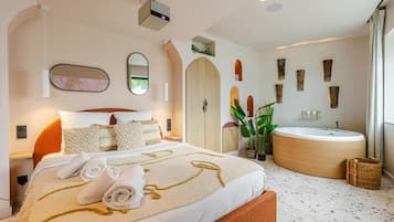 A modern hotel room with a large bed, a round bathtub, and a large mirror.