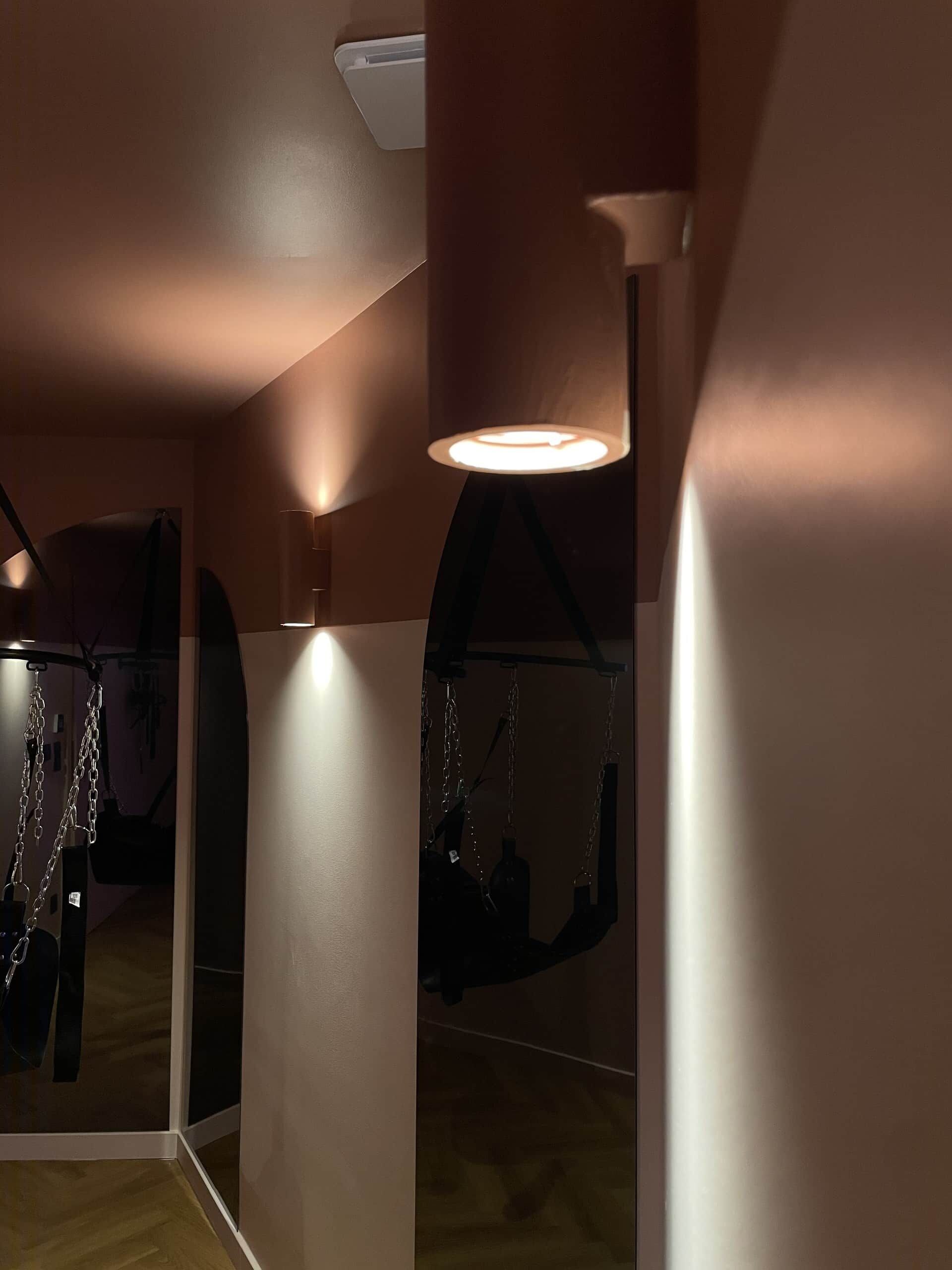 A room with a hanging swing, a wall-mounted lamp, and a ceiling vent.