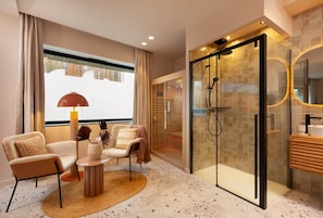 A modern bathroom with a glass shower enclosure, a vanity with a mirror, and a seating area with a lamp and chairs. - Romantic Suite in Ibiza | Sauna | Spa (Strasbourg)