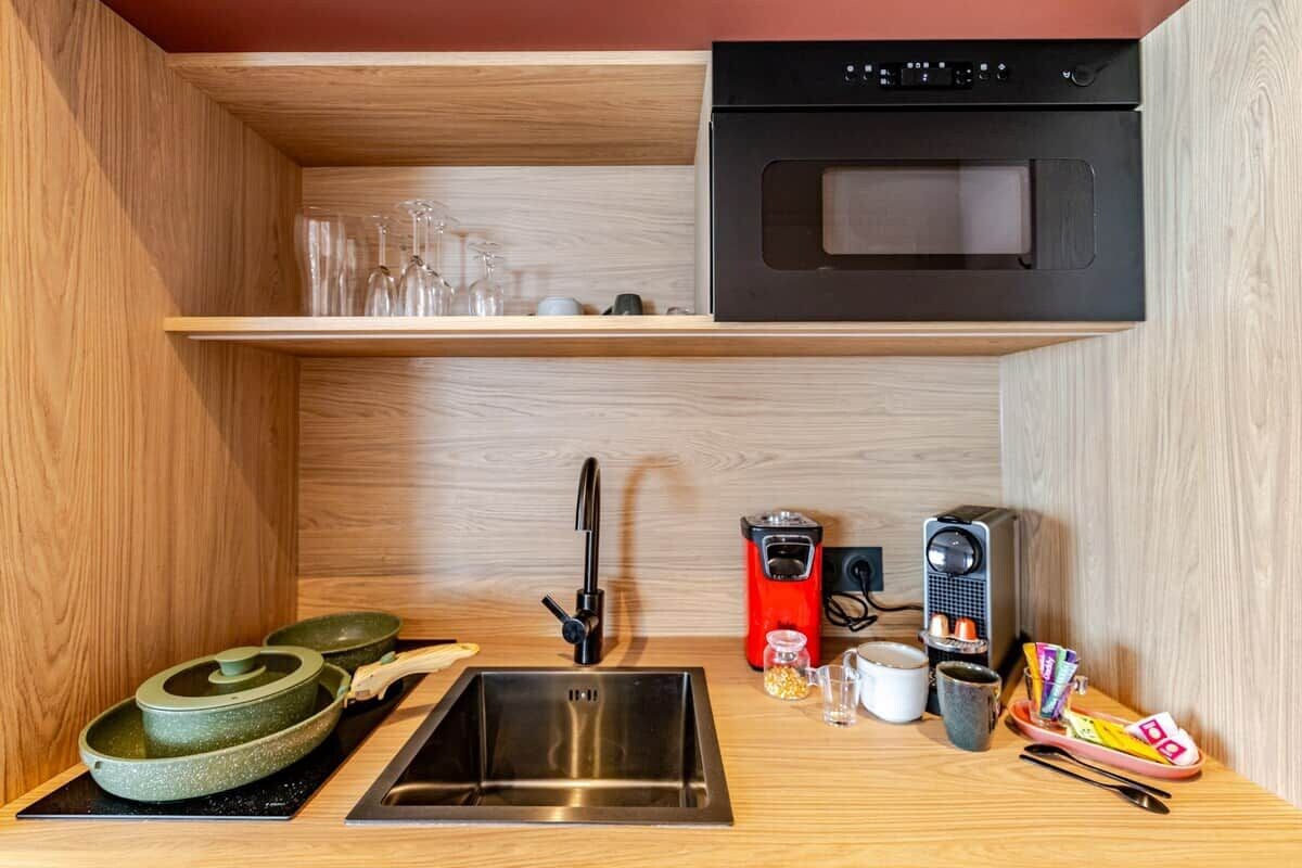 A compact kitchen with a built-in oven, a sink, and a coffee maker.