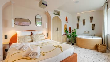 Une chambre moderne avec un grand lit, une baignoire intégrée et une grande fenêtre.