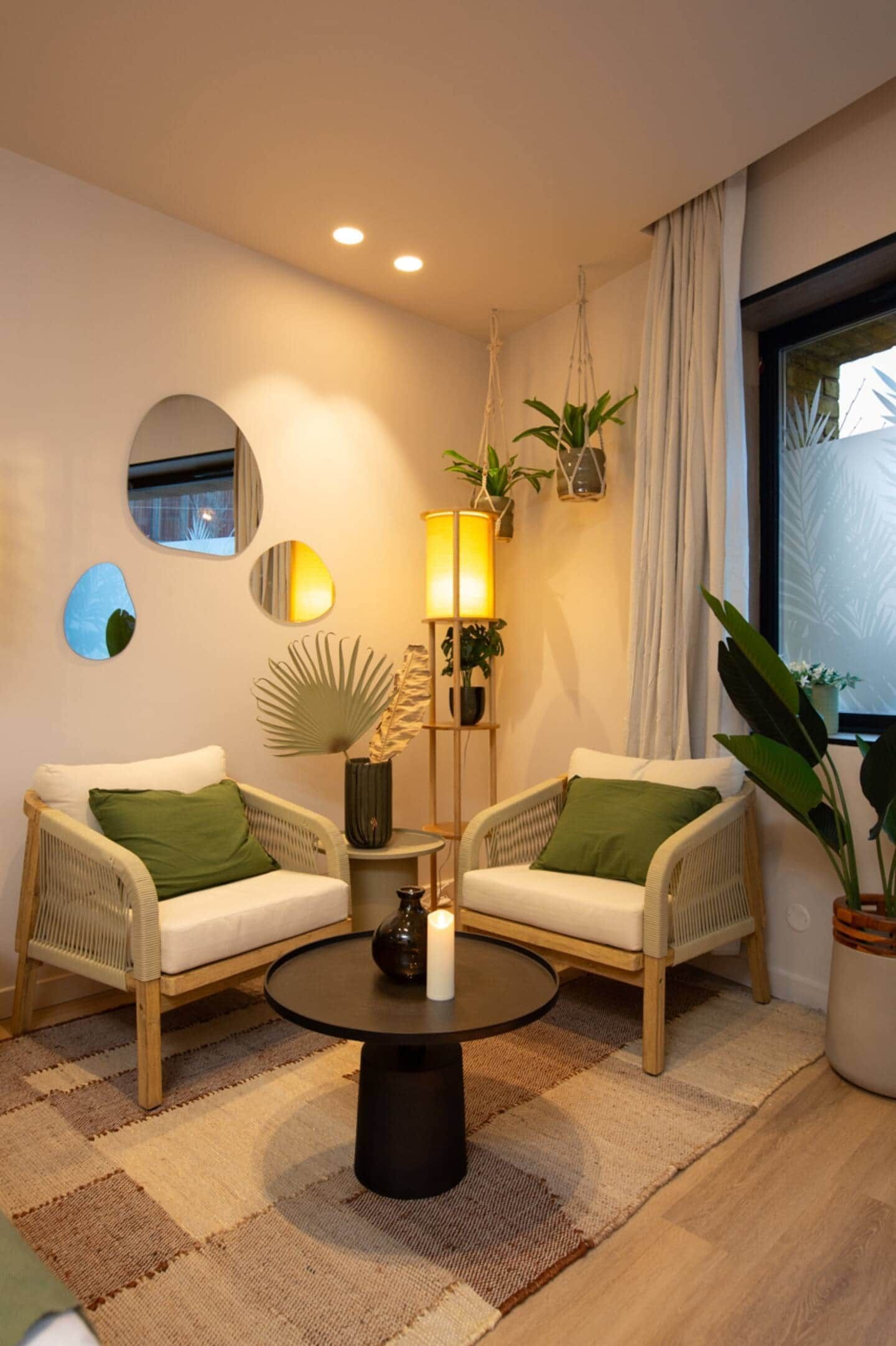 Un salon chaleureux avec deux fauteuils en osier, une table basse ronde et un lampadaire.