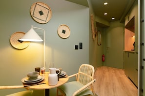 A dining area with a round table, a white chair, a lamp, and woven wall decorations. - Romantic Suite in Bali | Jacuzzi | Spa (Strasbourg)