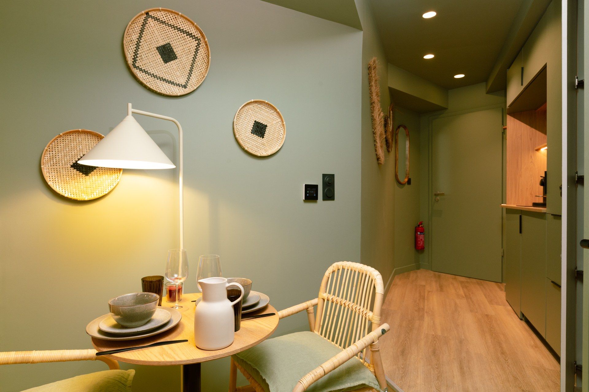 A dining area with a table set for two, a lamp, and wall-mounted baskets.