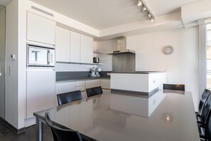 A modern kitchen with a built-in oven, a coffee maker, and a clock on the wall. - Apartment by Belgian Coast With Sea Views (Blankenberge)