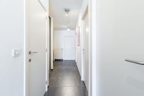 A narrow hallway with white walls and a tiled floor, leading to a door at the end. - Apartment by Belgian Coast With Sea Views (Blankenberge)
