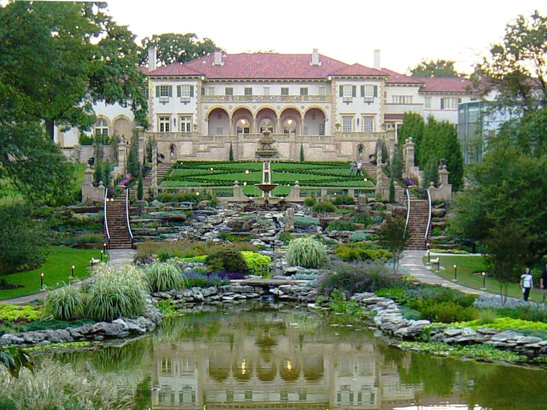 A large building with a fountain, a pond, and a well-maintained garden.