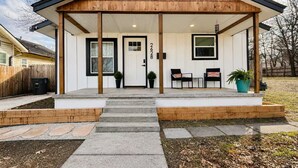 Una casa moderna con un porche cubierto, una puerta principal y un buzón.