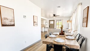Comedor con una mesa de madera preparada para cuatro personas, rodeada de sillas negras.