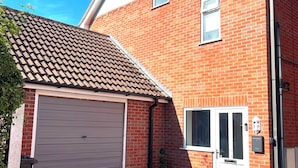 Ein zweistöckiges Ziegelhaus mit Garage, Eingangstür und kleinem Fenster.