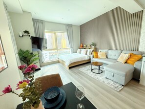 Ein modernes Schlafzimmer mit Bett, Sofa und Fernseher.