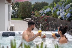A hot tub with two people enjoying drinks. - Quinta Baviera: Your Charming Retreat with a Jacuzzi on São Miguel Island (Açores)
