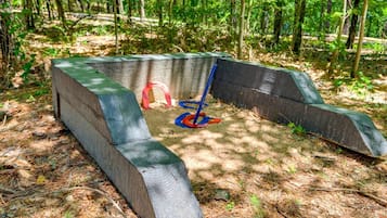 A concrete structure in a forested area with a blue shovel and a red tool.