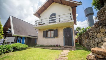 A two-story building with a balcony, a stone wall, and a stone pathway leading to the entrance.