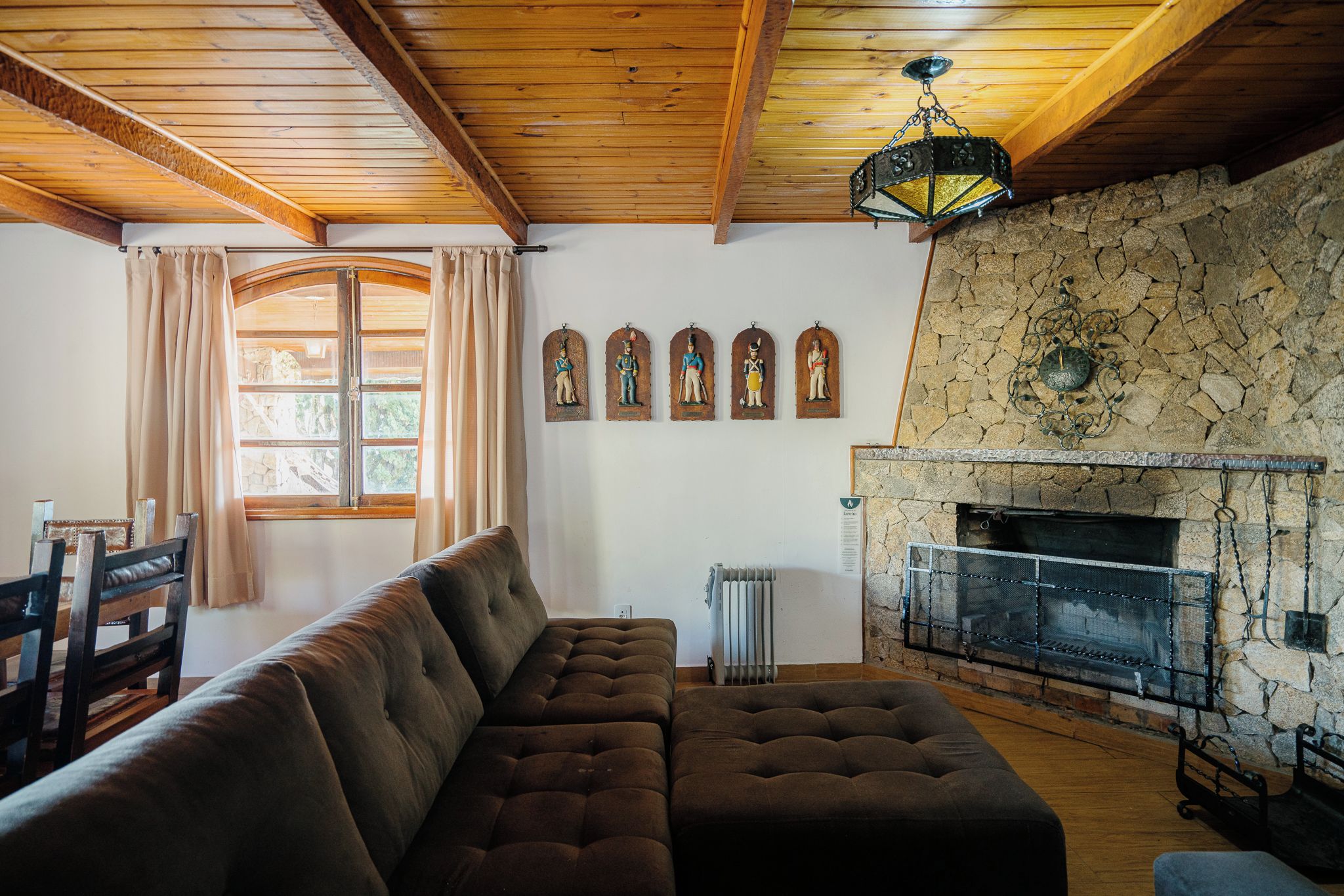 Una sala de estar con chimenea de piedra, techo de madera y un sofá grande y acolchado.