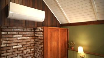Habitación en esquina con pared de ladrillo, puerta de madera y unidad de aire acondicionado blanca.