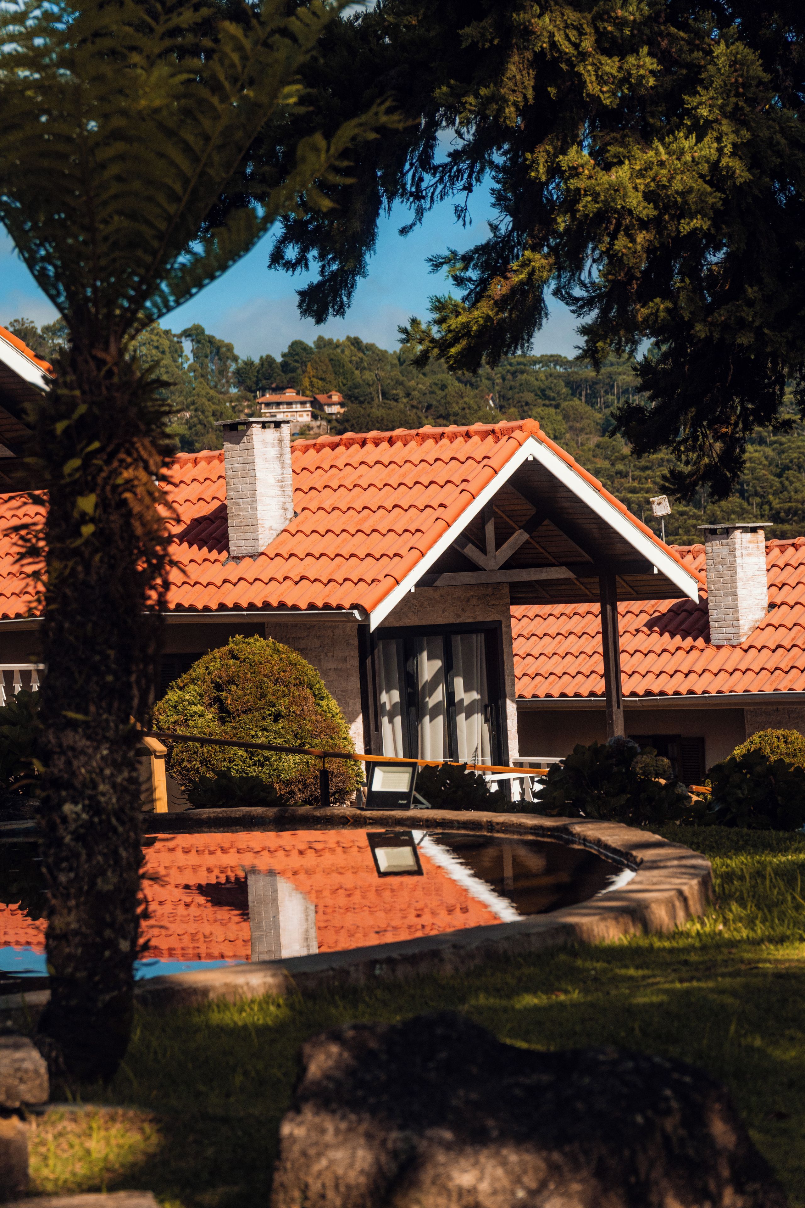 Una casa con techo de tejas rojas, un porche cubierto y una piscina.