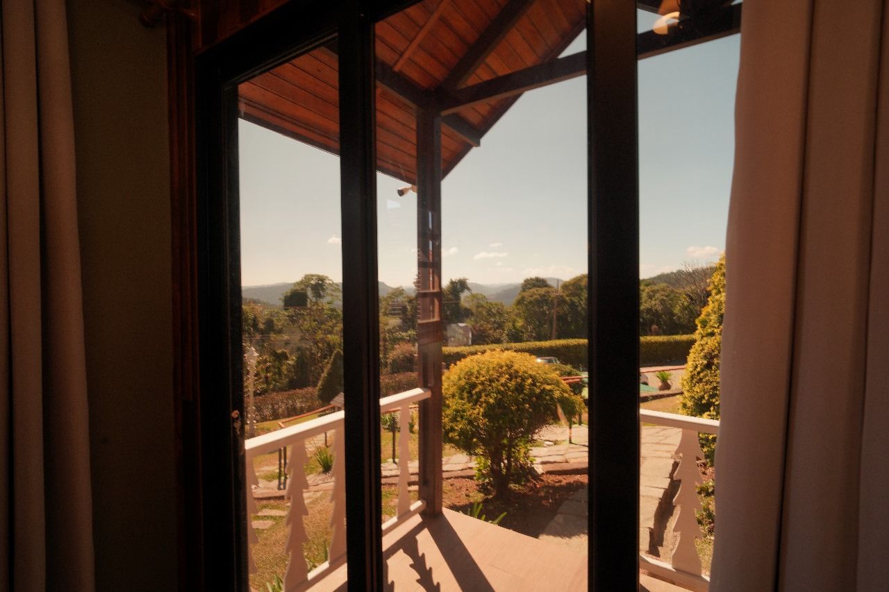 Una habitación con un amplio ventanal con vistas a un jardín ajardinado y colinas lejanas.