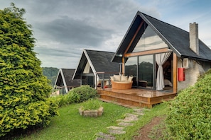 A modern house with a large deck, glass doors, and a view of the surrounding landscape. - Pousada das Pedras (Camanducaia)