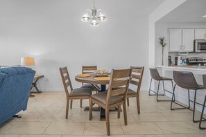 Eine moderne Küche mit weißen Schränken, einem Esstisch mit Stühlen und einer Pendelleuchte.