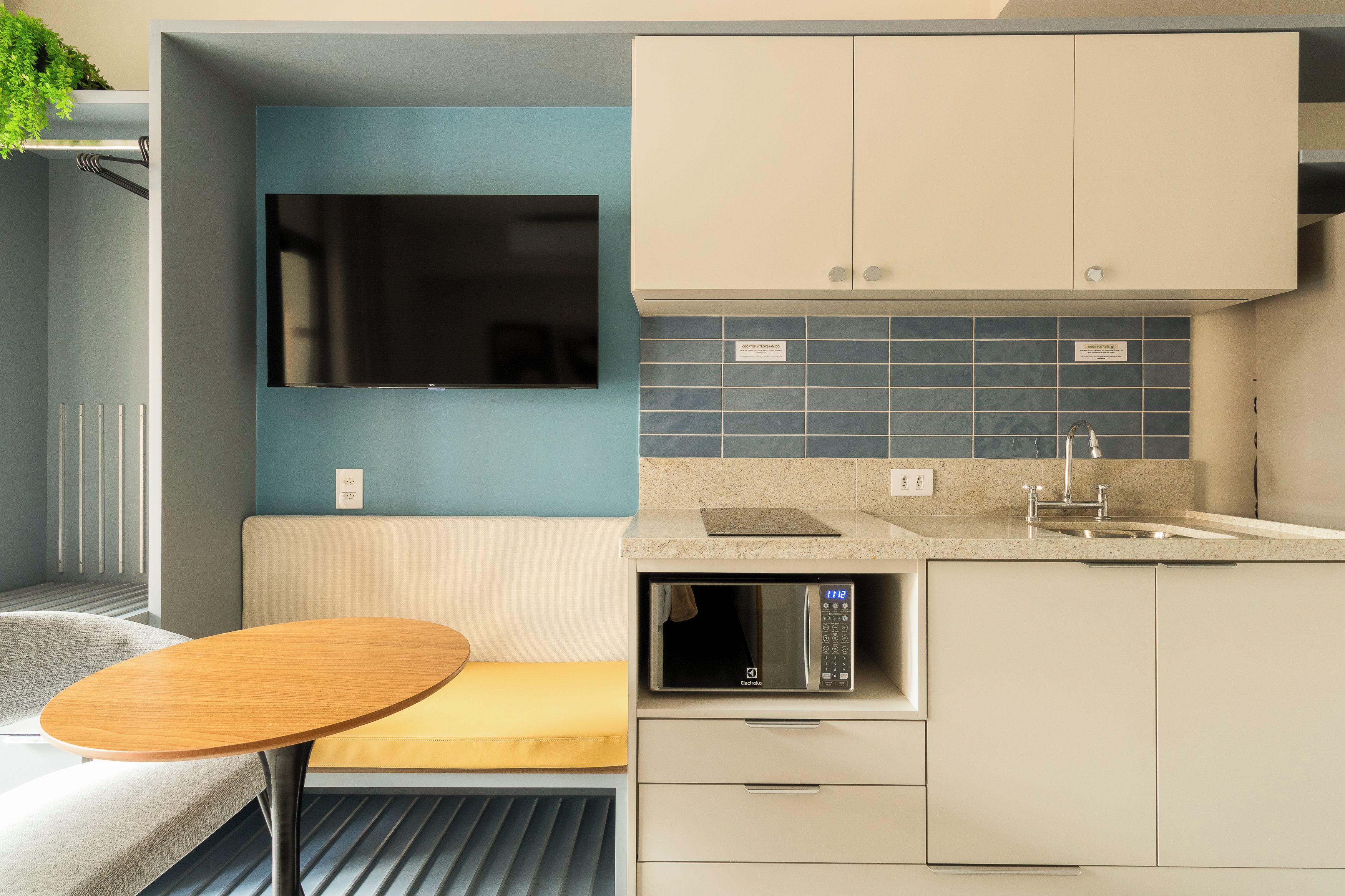 A compact kitchenette with a built-in microwave, a sink, and a small dining area with a round table.