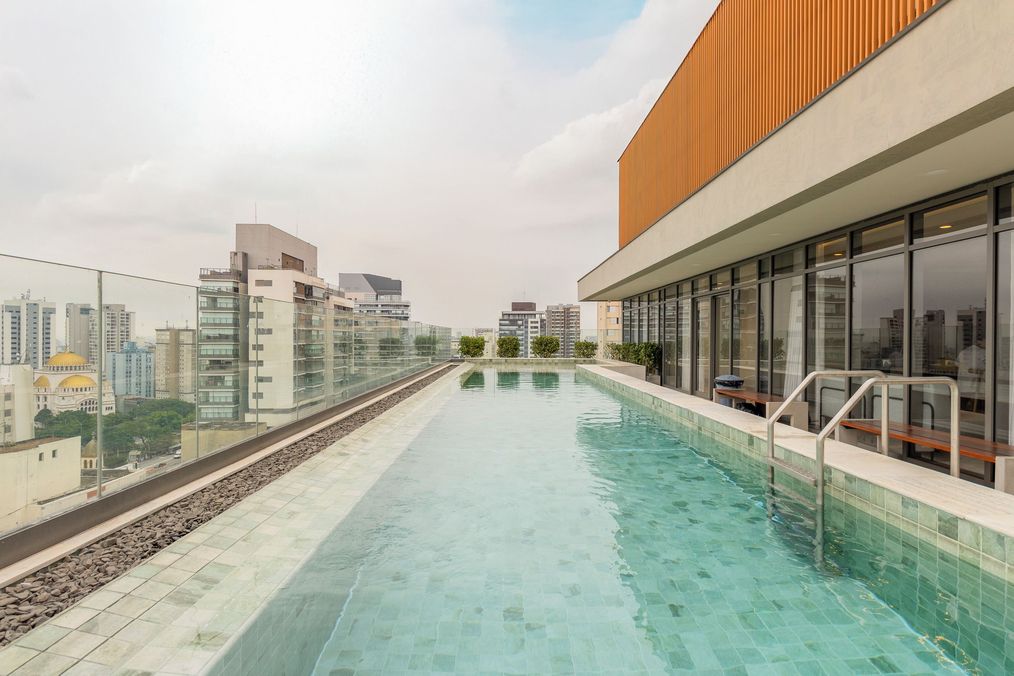 A rooftop swimming pool with a city view, surrounded by modern buildings.