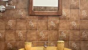 A bathroom with a yellow sink, a mirror, and decorative tiles. - Vrbo Property (Benavila)