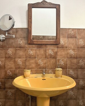 Une salle de bain avec un lavabo jaune, un miroir et des carreaux décoratifs.