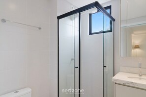 A modern bathroom with a glass shower enclosure, a white toilet, and a marble sink. - Apt. w/ Balcony in Condo. w/ Pool Mcb1003 (Picarras)